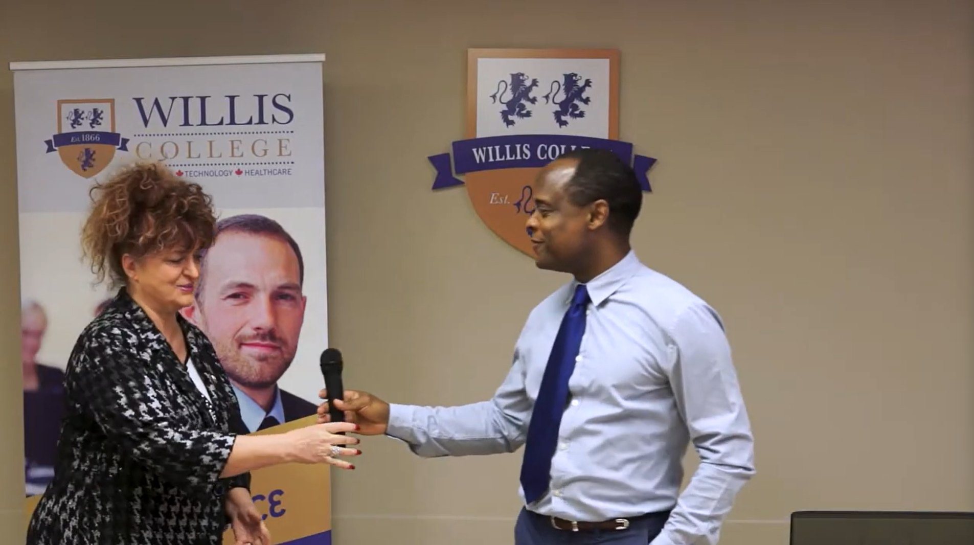 Antoine Joseph handing the microphone to a participant at a Lion's Den event at Willis College